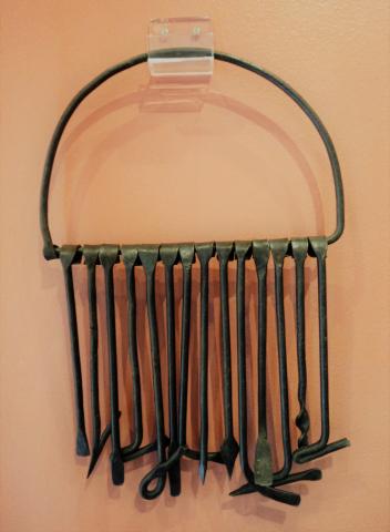 Insígnias - Ferramenta de Ogum - Há uma ocorrência de inúmeras ferramentas confeccionadas para Ogum, orixá do ferro. A mais recorrente é o molho de Ogum. É composta por hastes de ferro batido, representando ferramentas, em miniatura, ligadas a simbologia de Ogum. São foices, enxadas, martelos, alicates, tesouras, cavadores, espadas, pás, ancinhos ou instrumentos típicos do trabalho do ferreiro. O número de hastes é tradicionalmente impar, com recorrência do sete, e vinte e um, também quatorze, e ficam presas a um arco, confeccionado no mesmo material